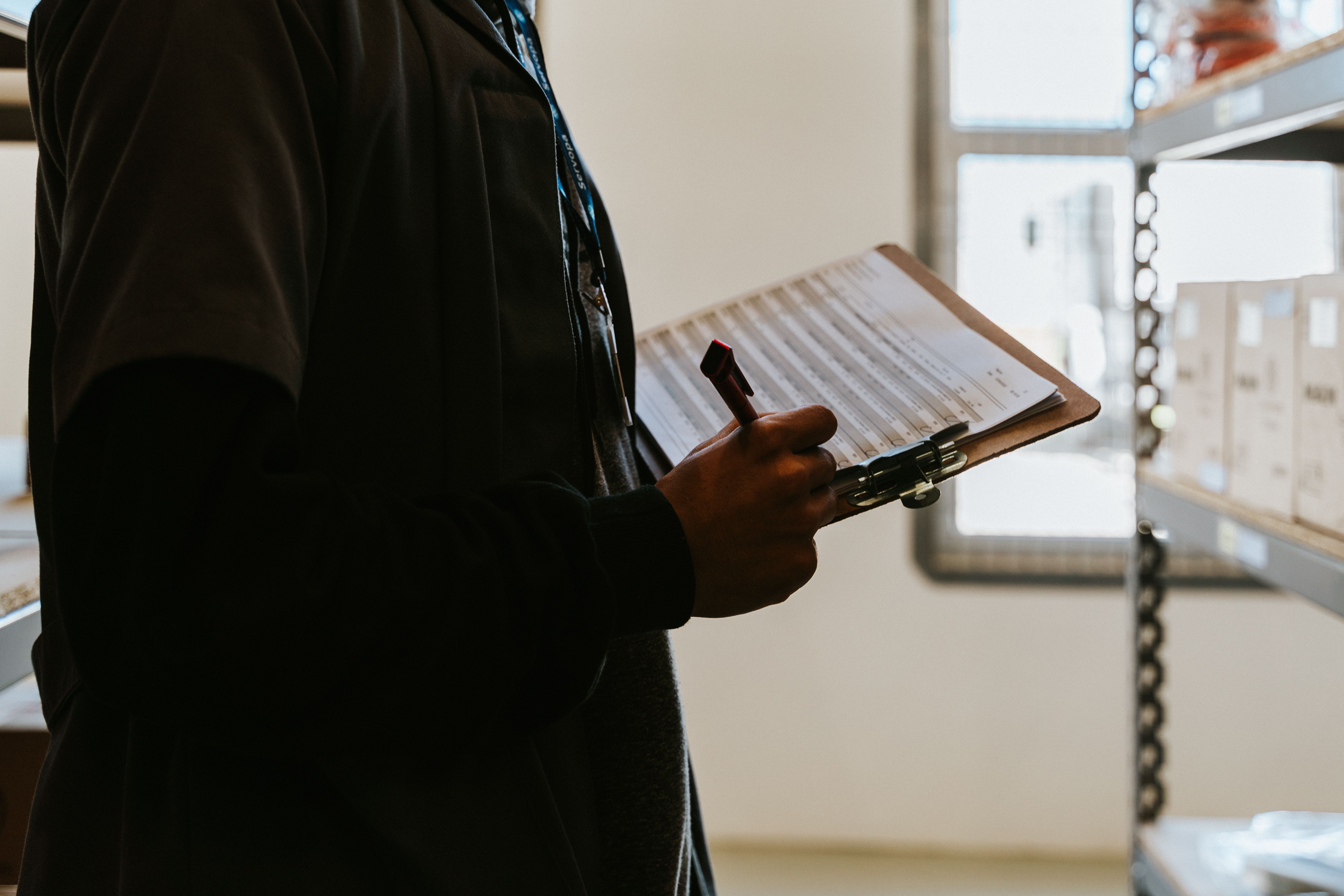 Close-up of a hand running through an asset checklist on a clipboard